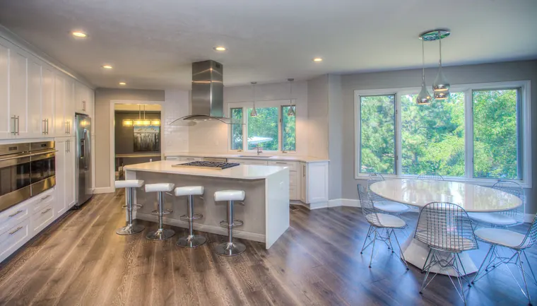 Modern white kitchen with installed wall cabinets, tall panels, and a central island
